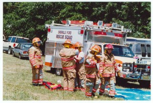 Fire Fighters putting on their uniforms outside next to an ambulance