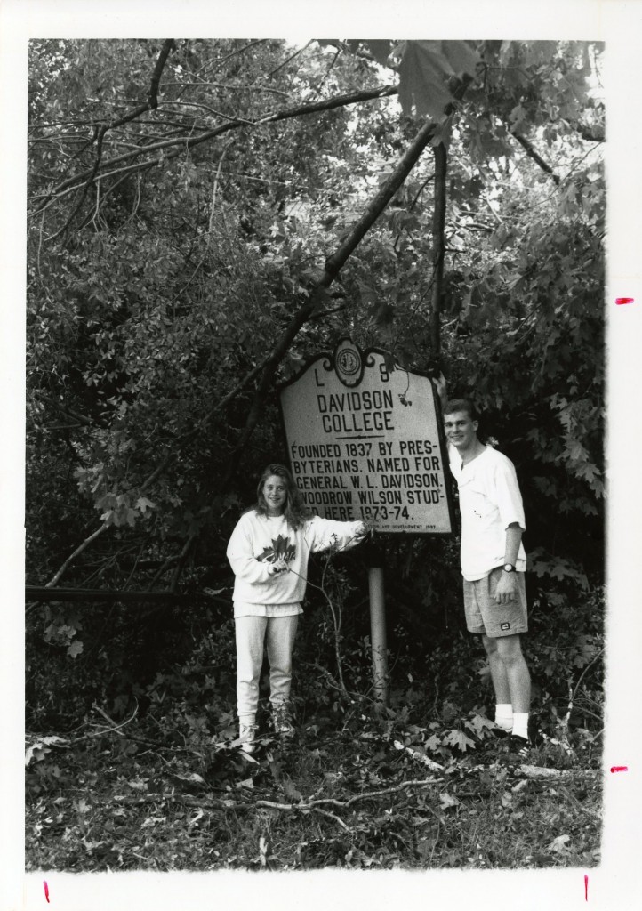 Students with the Davidson College historical marker on campus, behind them are multiple broken branches hanging and on the ground, illustrating the amount of debris on September 22, 1989.