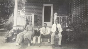 Hood Norton and family sitting on the steps of their front porch