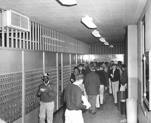 Area with students PO boxes in the 1960s, many students gathered in front of the samll square boxes in the walls