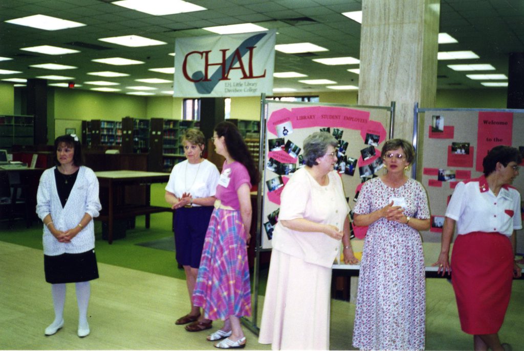 Library staff, including Jan (in the pink skirt and shirt), gather in the lobby of E.H. Little Library, circa 1998.