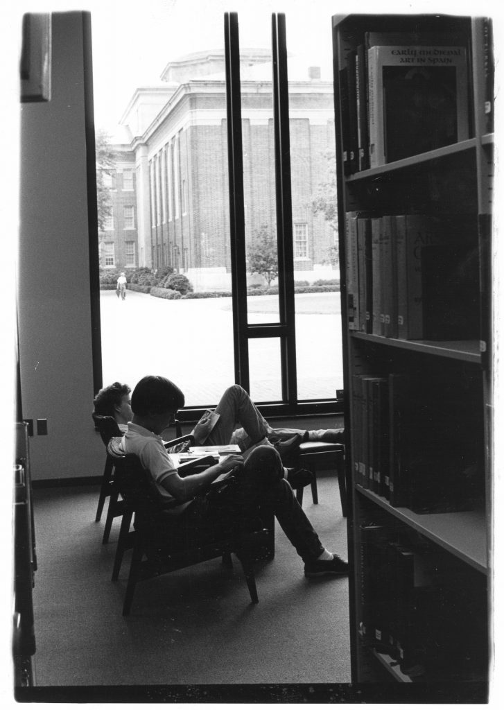 Two students study by a window on the first floor of Little Library, with Chambers visible in the background, 1980s.