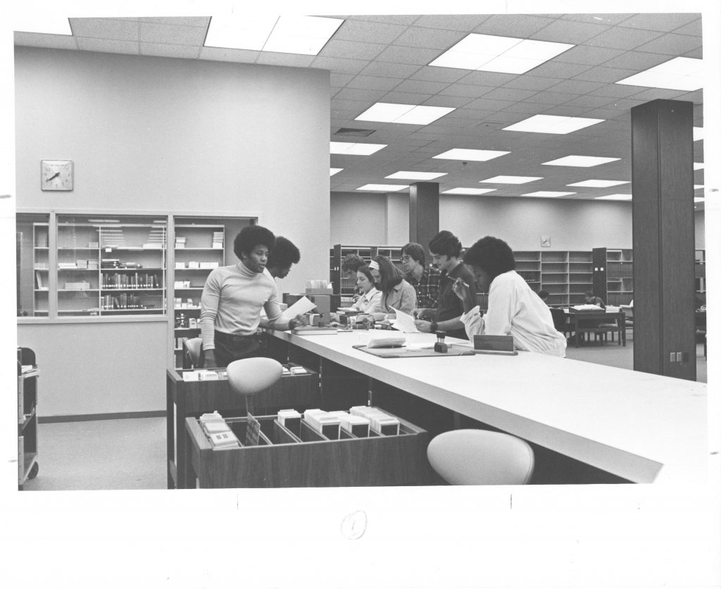 A group of students gather at the circulation desk in Little Library, September 18, 1974.