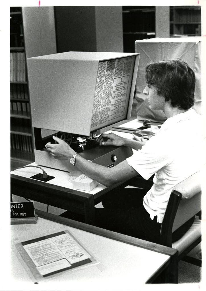 A student uses the microfilm reader in Little Library, circa 1980s.