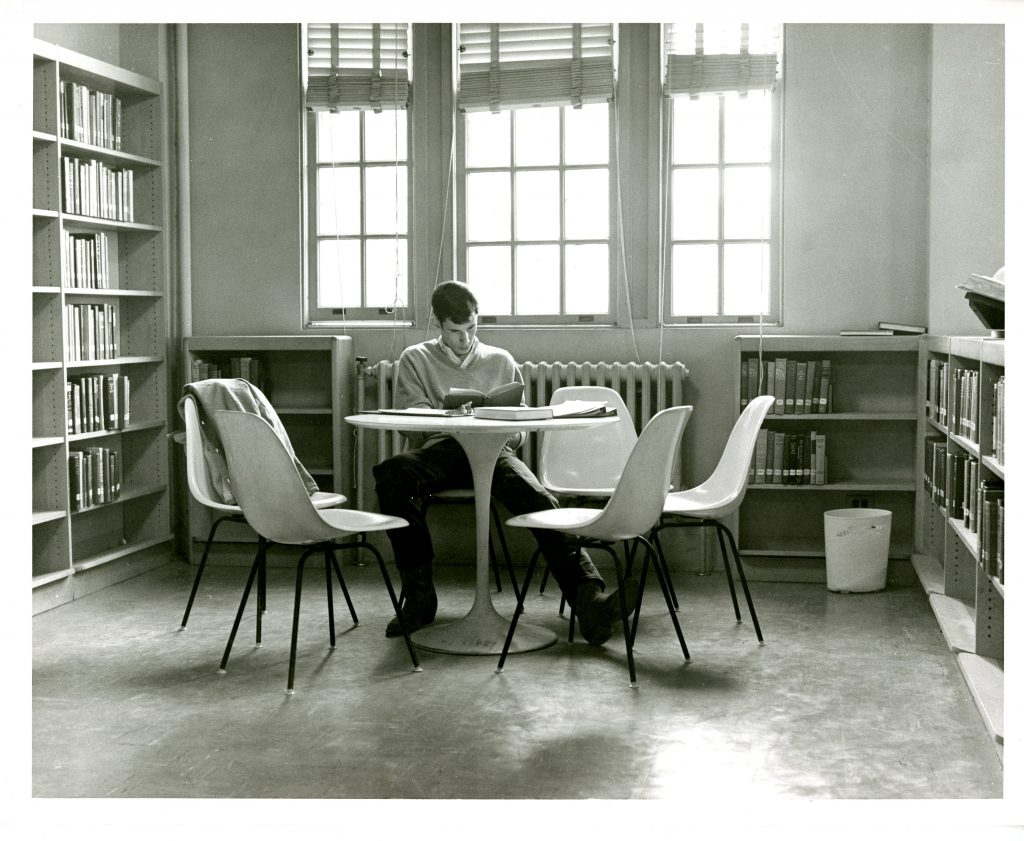 A student studies at a table in Grey Library (now Sloan Music Center) while wearing cowboy boots, 1968.