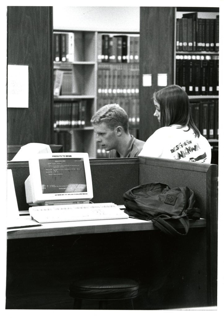 Two students use a computer in Little Library, circa 1993.