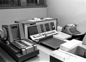 An IBM 1620 Computer from the early 1960s sits atop a table. A locked shelf is in the background